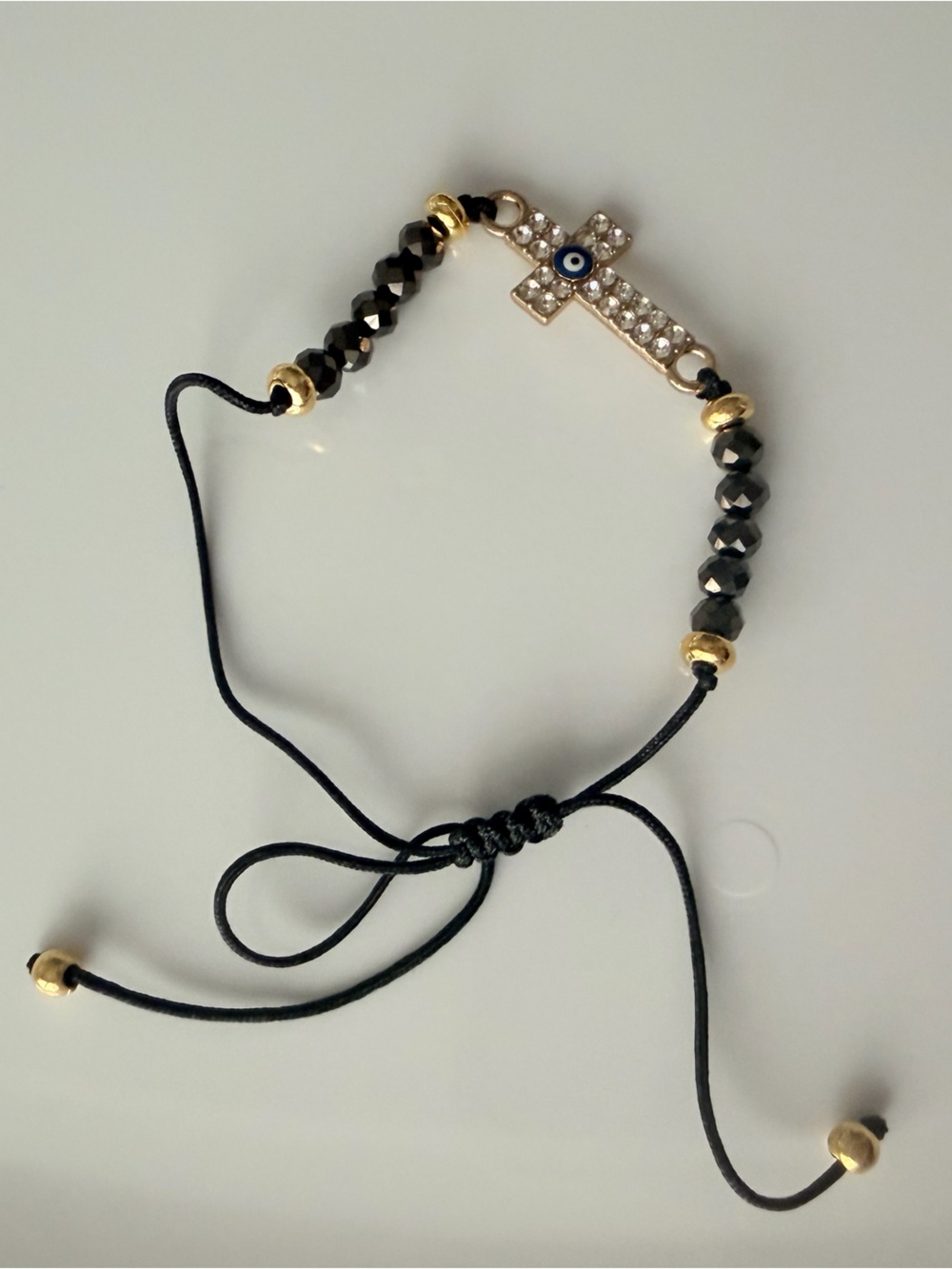 Adjustable Black Beaded Bracelet with Gold Cross and Blue Eye Accent